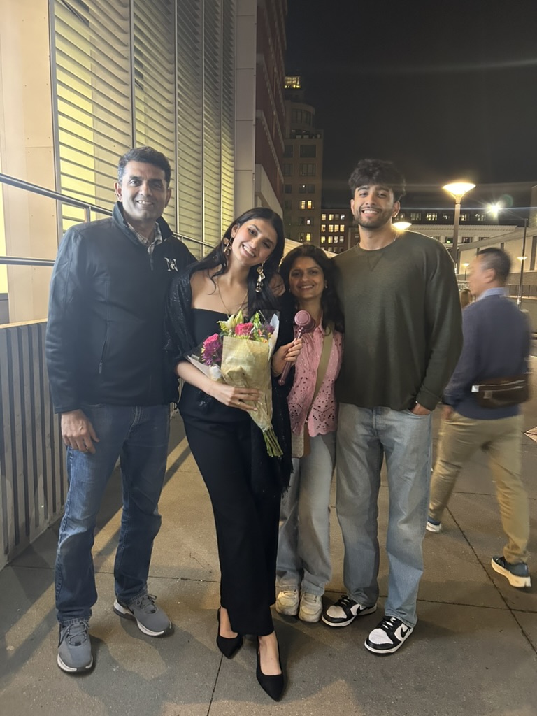 Sidd with his family outside at night, celebrating with flowers